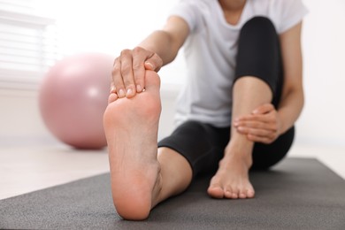 Photo of Woman suffering from foot pain at home, closeup