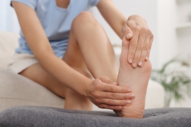 Photo of Woman suffering from foot pain at home, closeup