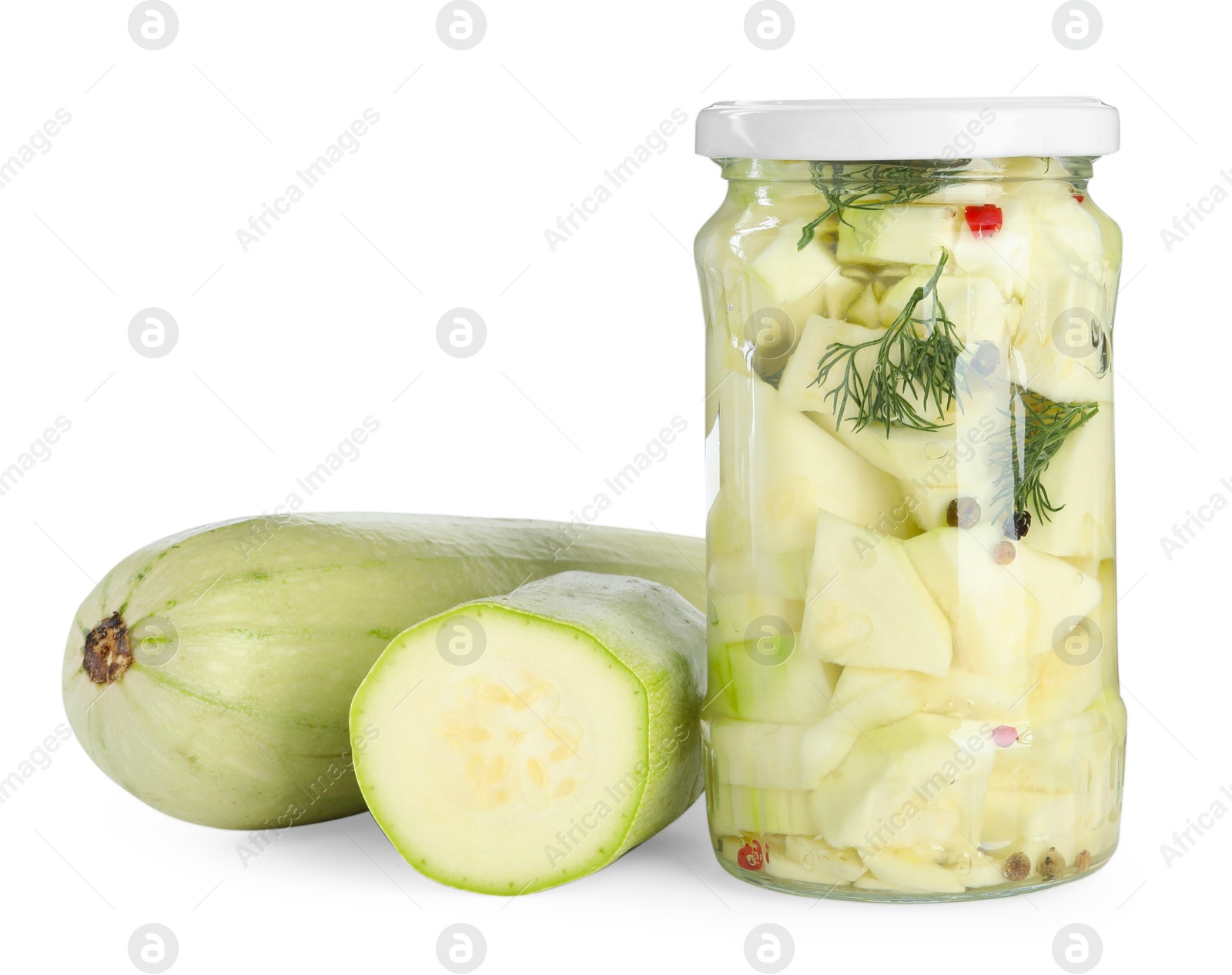 Photo of Tasty pickled zucchinis in jar and fresh vegetables isolated on white