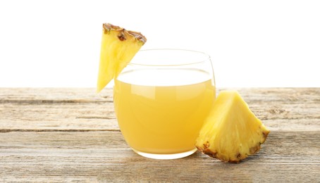 Photo of Tasty pineapple juice in glass and slices of fresh fruit on wooden table against white background