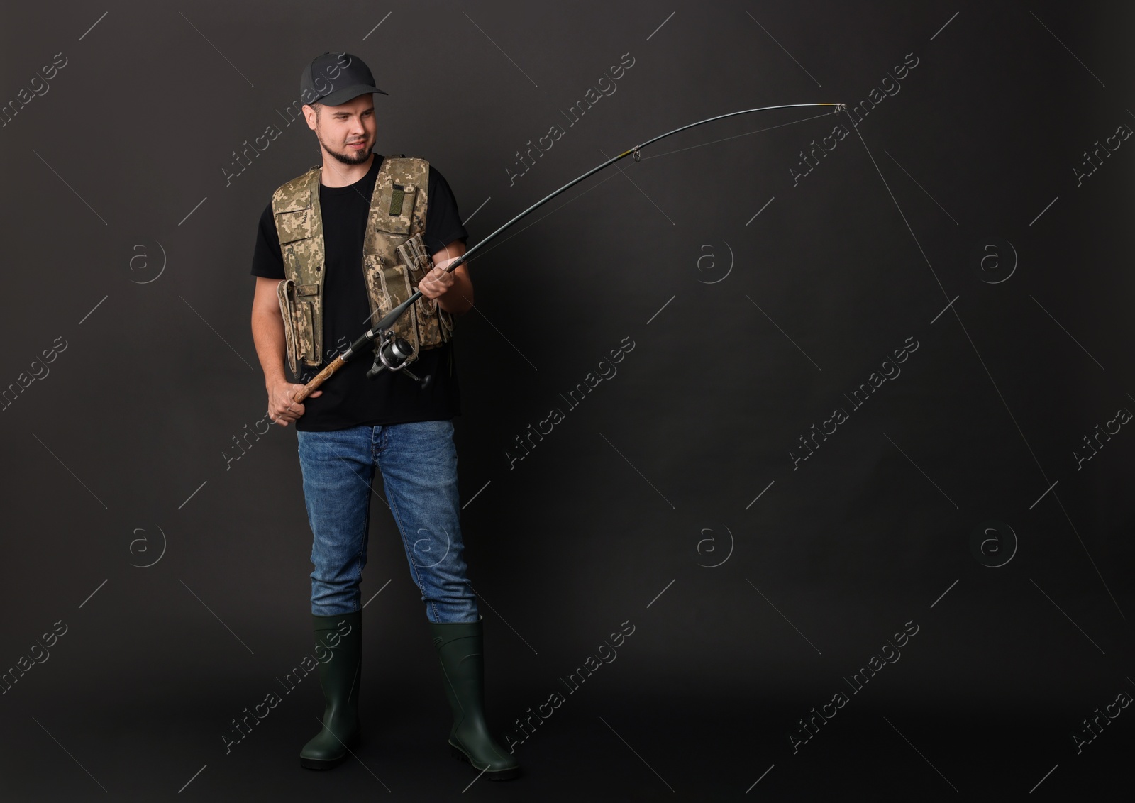 Photo of Fisherman with rod fishing against black background