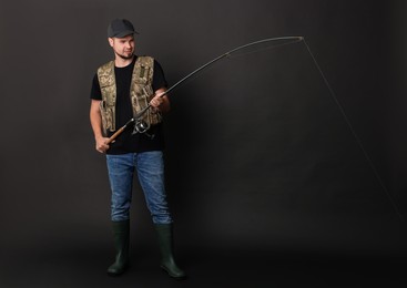 Fisherman with rod fishing against black background