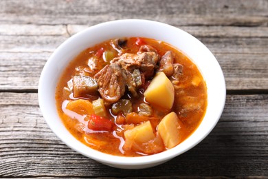 Photo of Delicious stew with vegetables in bowl on wooden table, closeup