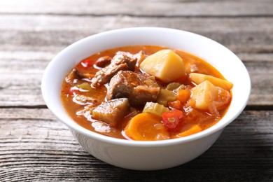 Delicious stew with vegetables in bowl on wooden table, closeup