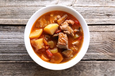 Photo of Delicious stew with vegetables in bowl on wooden table, top view