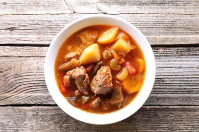 Photo of Delicious stew with vegetables in bowl on wooden table, top view