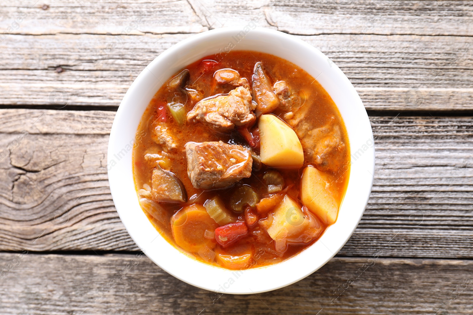 Photo of Delicious stew with vegetables in bowl on wooden table, top view