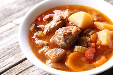 Photo of Delicious stew with vegetables in bowl on wooden table, closeup