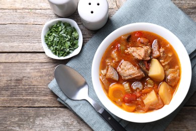 Photo of Delicious stew with vegetables in bowl, parsley and spoon on wooden table, top view