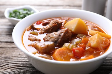 Delicious stew with vegetables in bowl on wooden table, closeup