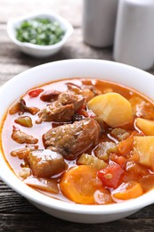 Photo of Delicious stew with vegetables in bowl on wooden table, closeup