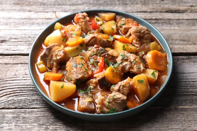 Photo of Delicious stew with vegetables on wooden table, closeup