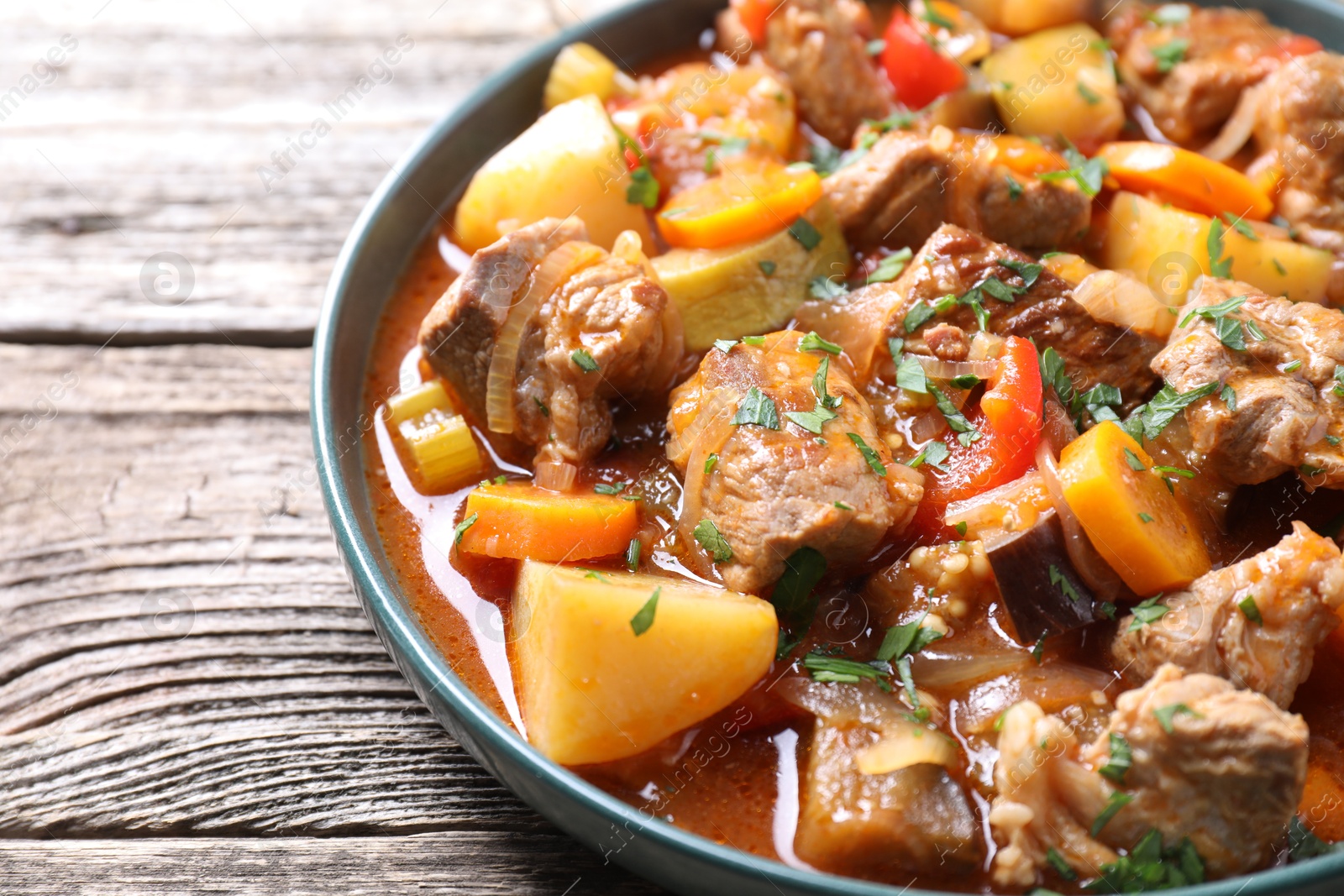 Photo of Delicious stew with vegetables on wooden table, closeup