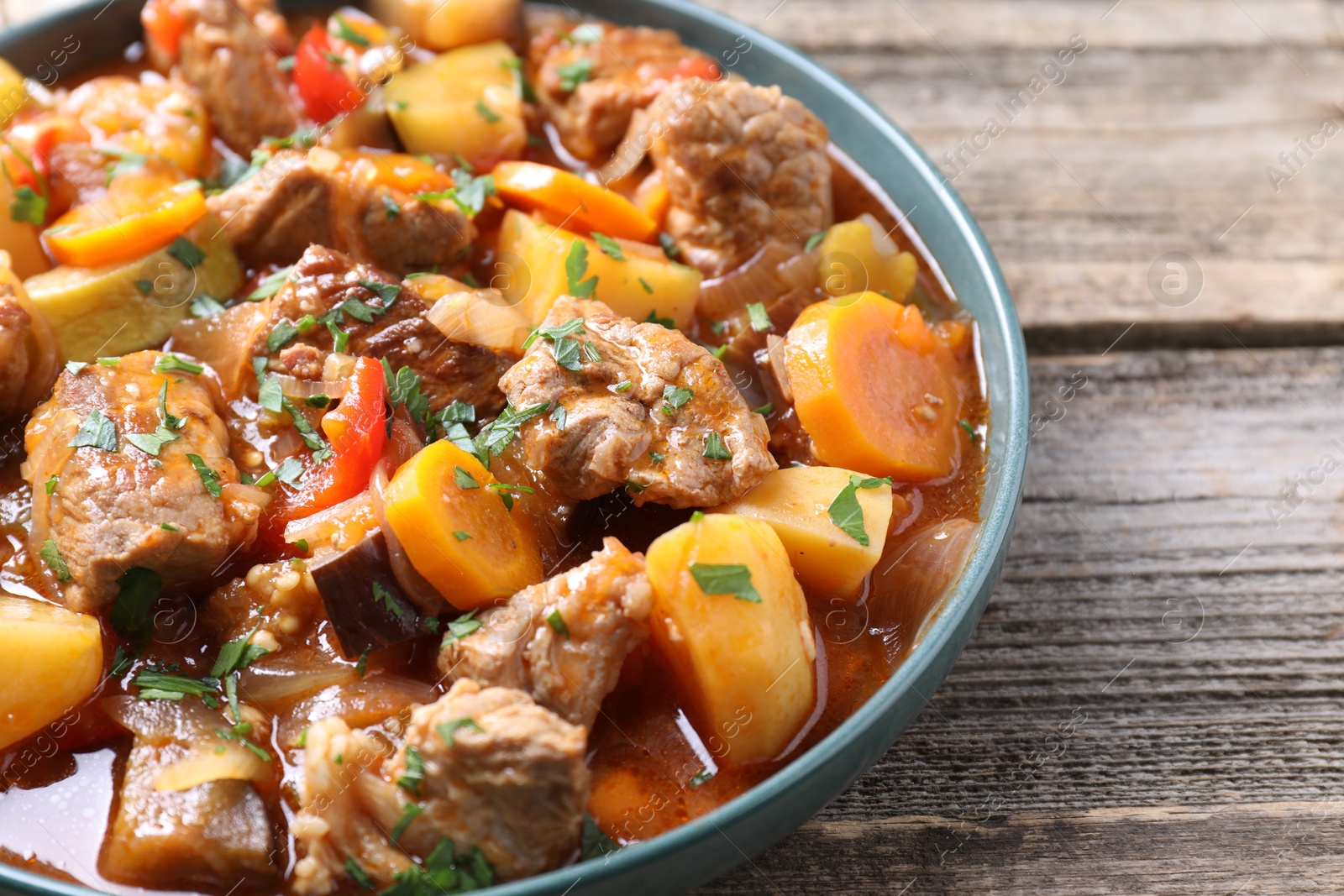 Photo of Delicious stew with vegetables on wooden table, closeup