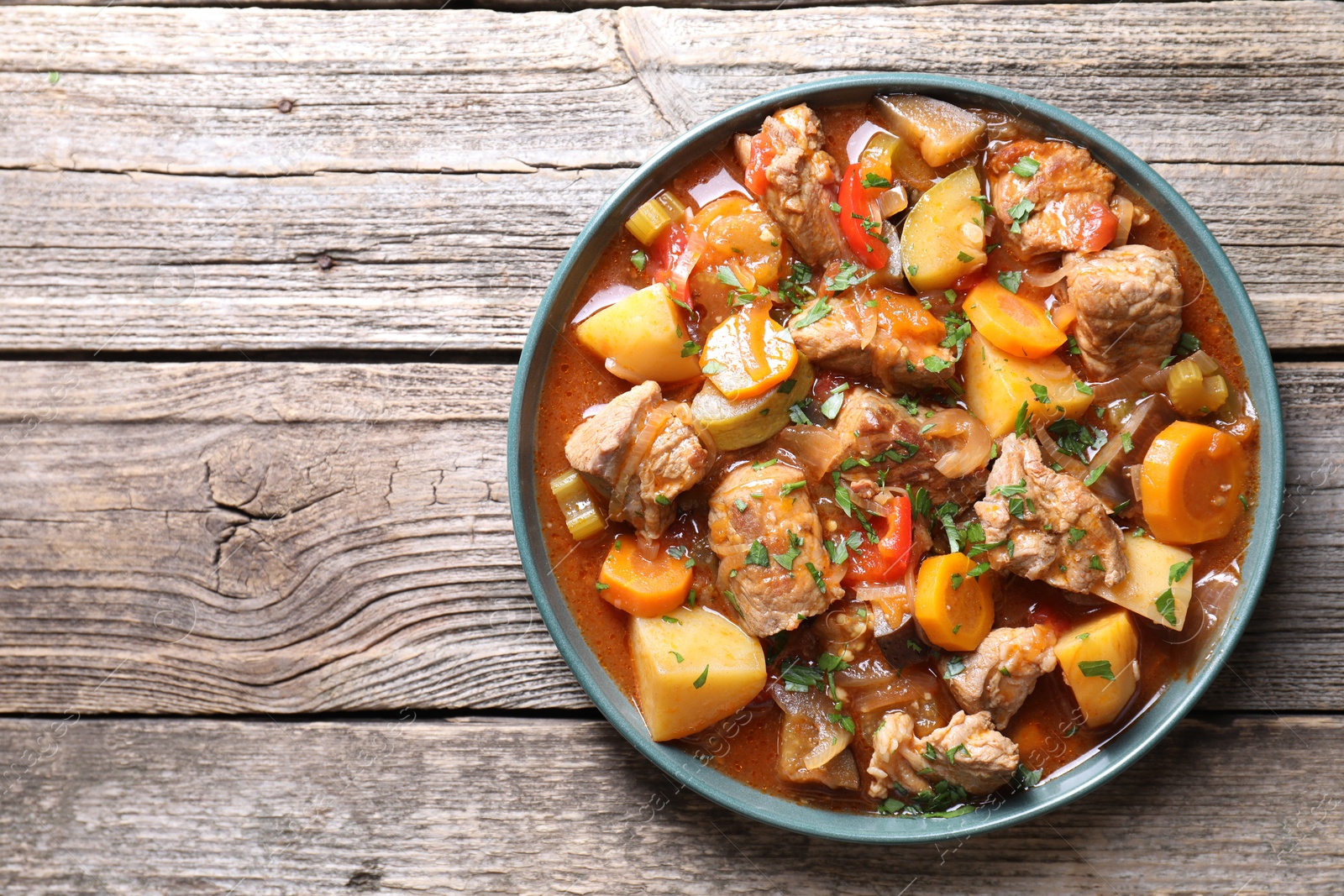 Photo of Delicious stew with vegetables on wooden table, top view. Space for text