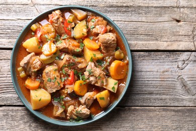 Photo of Delicious stew with vegetables on wooden table, top view