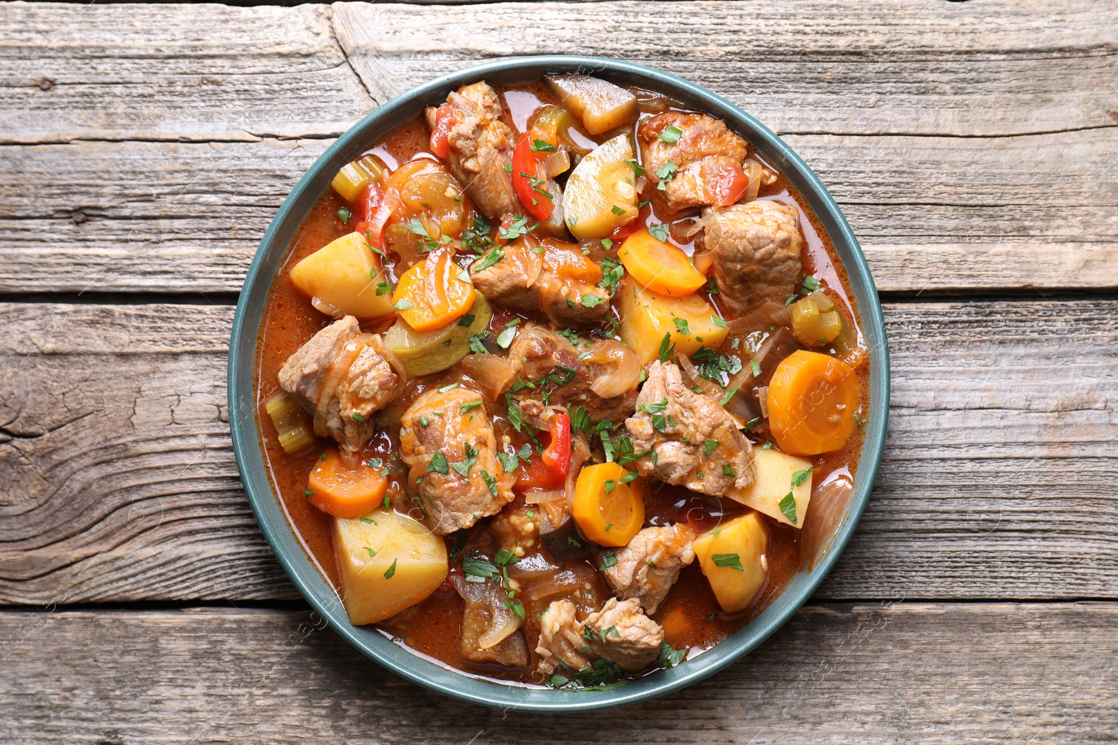 Photo of Delicious stew with vegetables on wooden table, top view