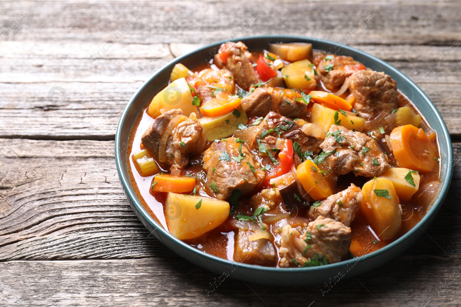 Photo of Delicious stew with vegetables on wooden table, closeup