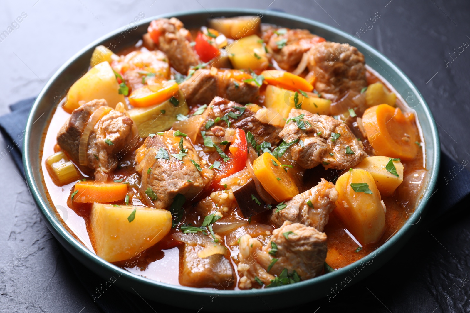 Photo of Delicious stew with vegetables on black table, closeup