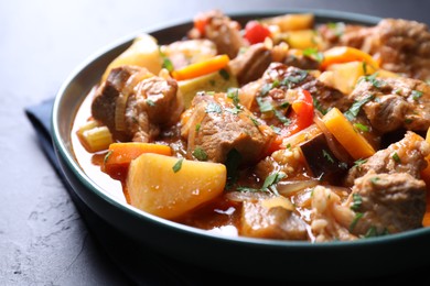 Photo of Delicious stew with vegetables on black table, closeup