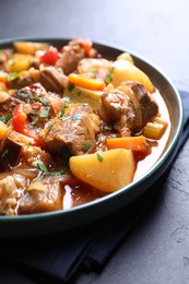 Photo of Delicious stew with vegetables on black table, closeup