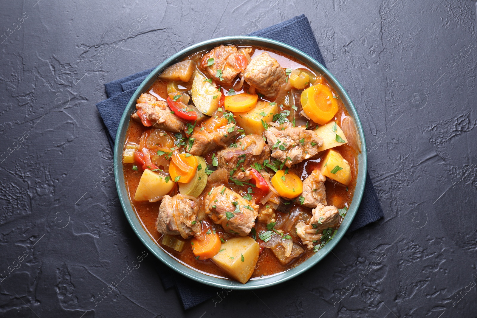 Photo of Delicious stew with vegetables on black table, top view