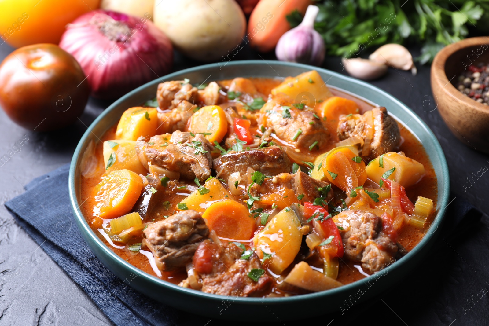 Photo of Delicious stew and different ingredients on black table, closeup