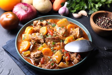 Photo of Delicious stew and different ingredients on black table, closeup