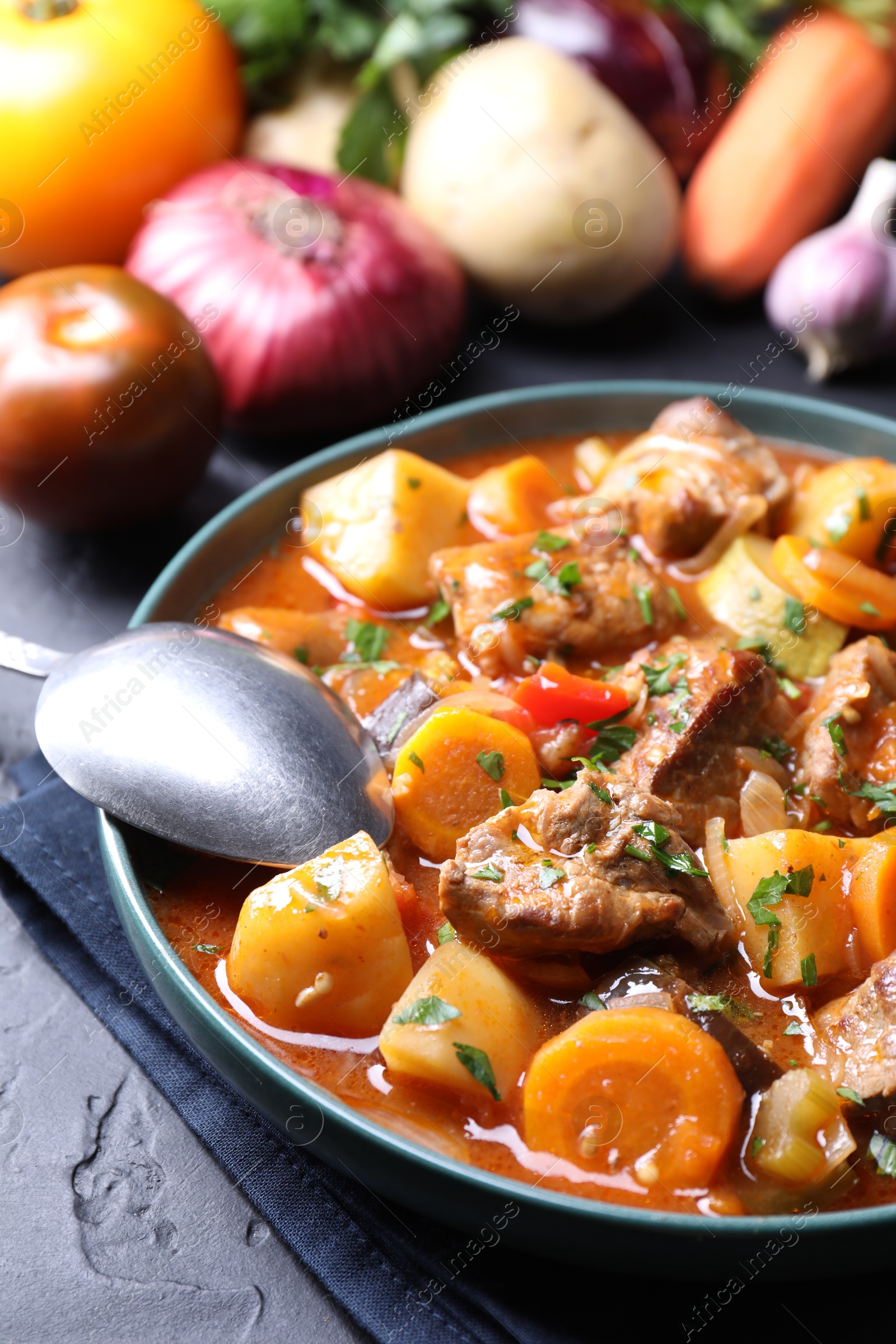 Photo of Delicious stew and different ingredients on black table, closeup