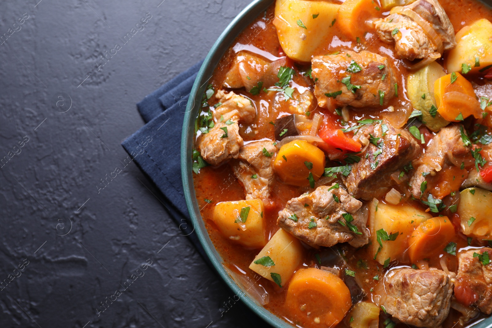 Photo of Delicious stew with vegetables on black table, top view