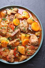 Photo of Delicious stew with vegetables on black table, top view