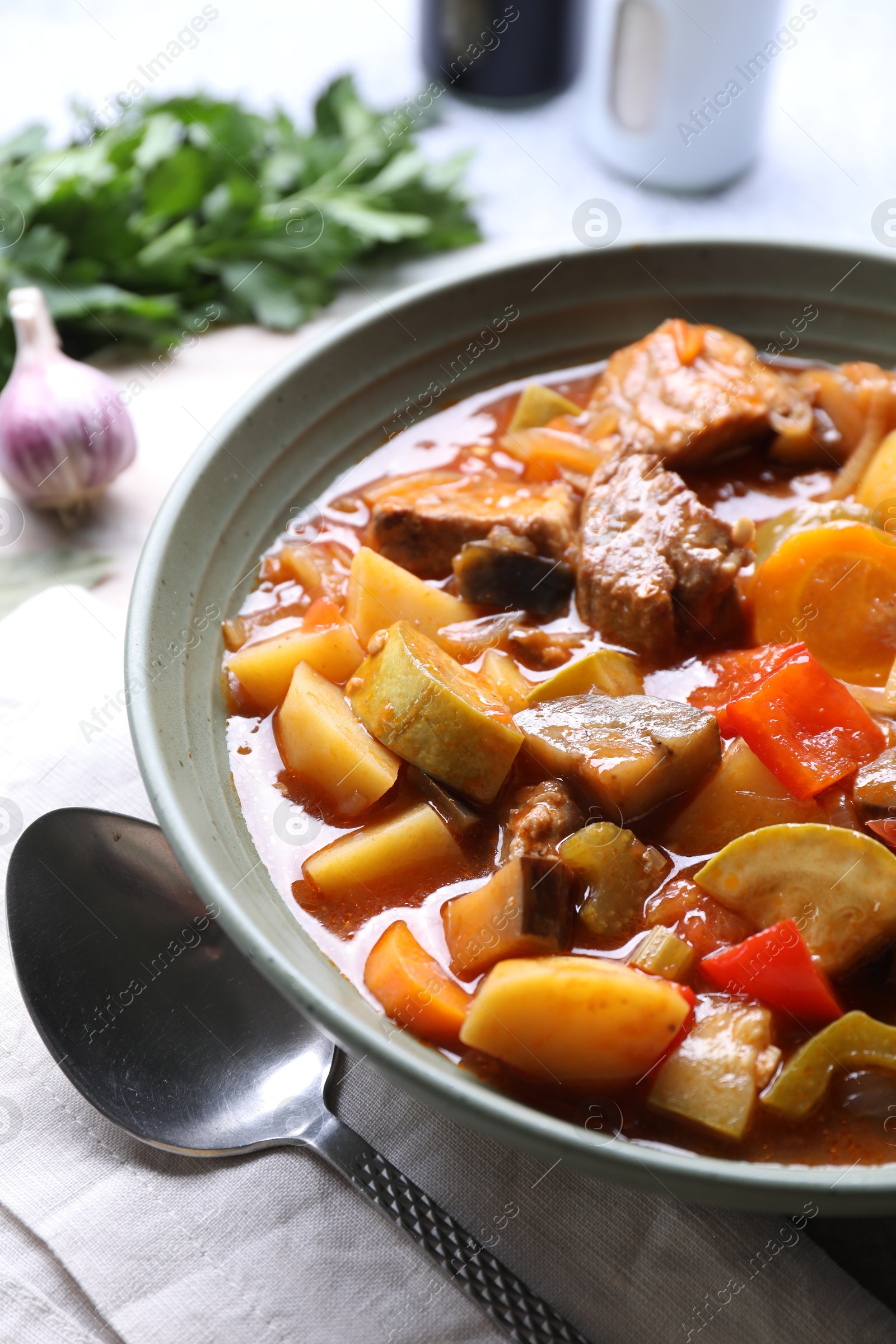 Photo of Delicious stew with vegetables in bowl and spoon on table, closeup