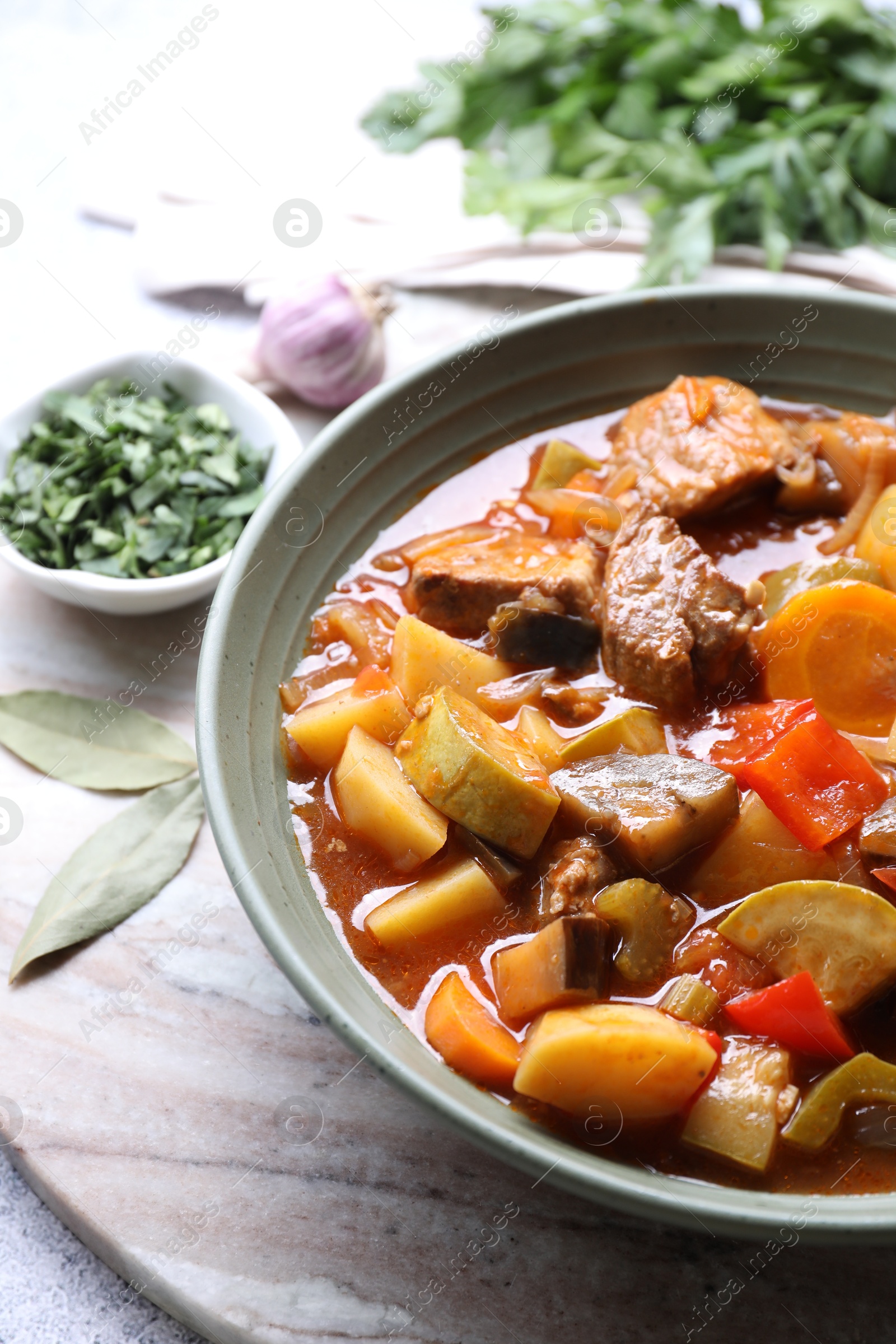 Photo of Delicious stew with vegetables in bowl and spices on table, closeup