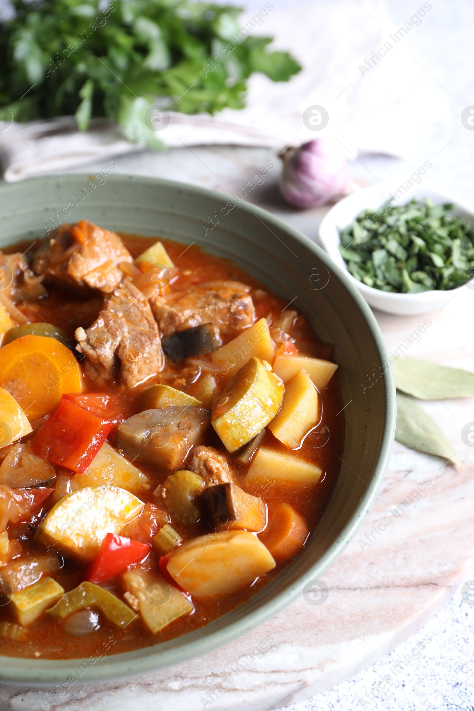 Photo of Delicious stew with vegetables in bowl and spices on table, closeup