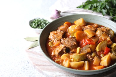 Photo of Delicious stew with vegetables in bowl and spices on table, closeup