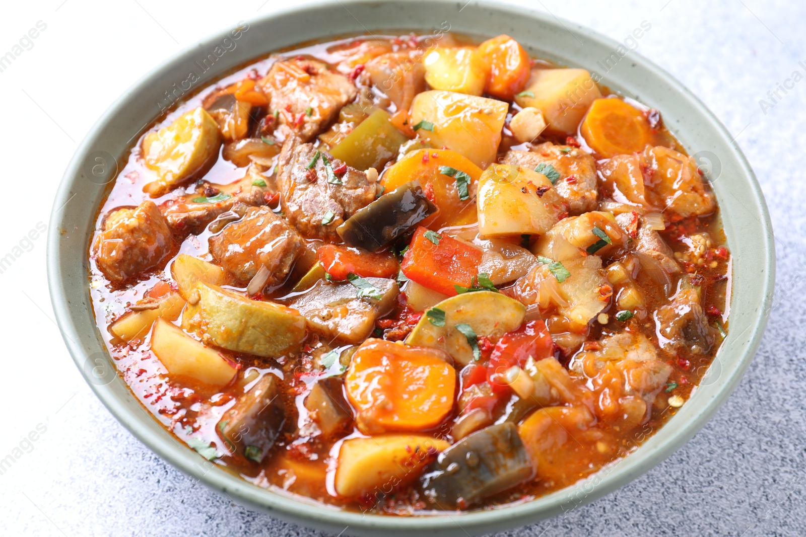 Photo of Delicious stew with vegetables in bowl on light grey table, closeup