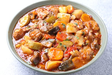 Photo of Delicious stew with vegetables in bowl on light grey table, closeup