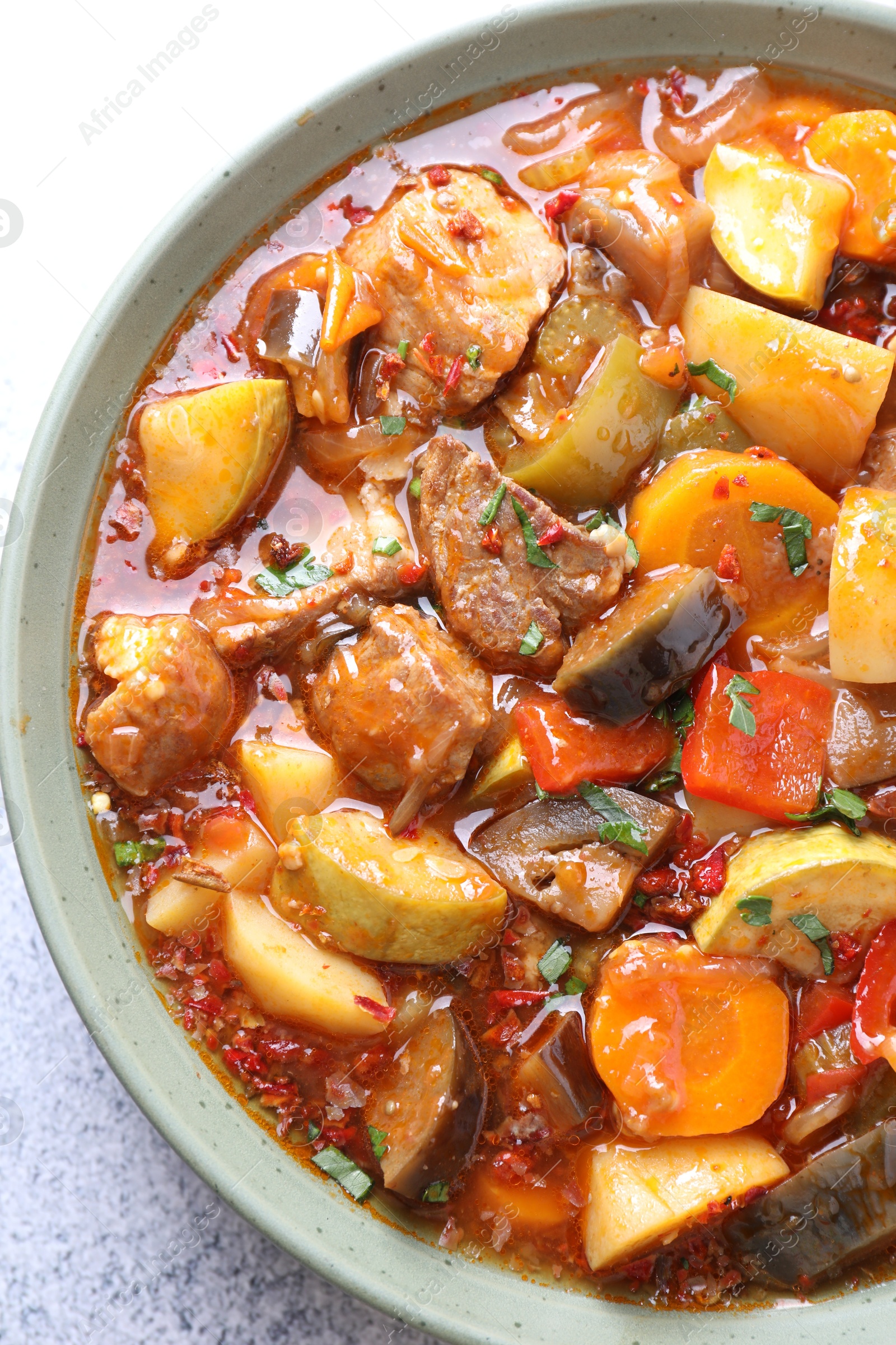 Photo of Delicious stew with vegetables in bowl on light grey table, top view