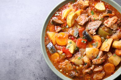 Photo of Delicious stew with vegetables in bowl on grey table, top view