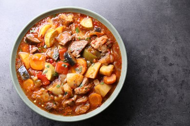 Photo of Delicious stew with vegetables in bowl on grey table, top view