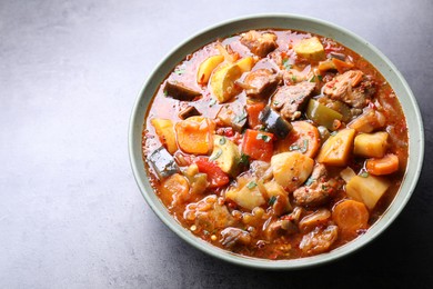 Photo of Delicious stew with vegetables in bowl on grey table, closeup