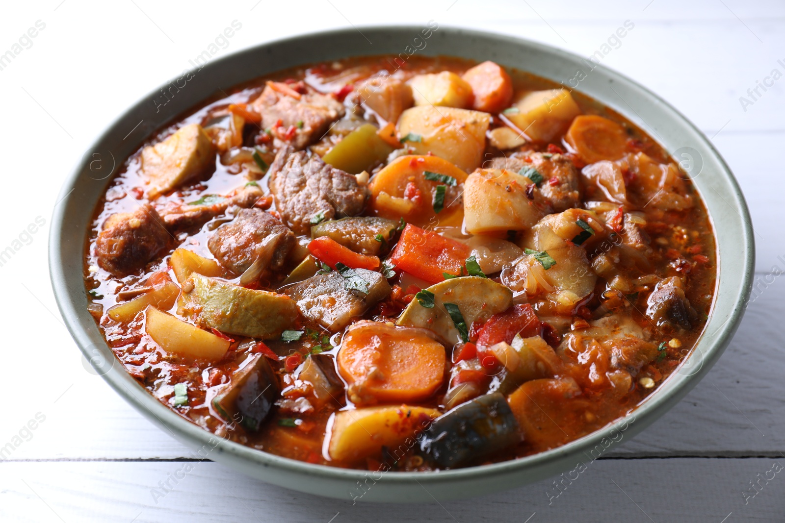 Photo of Delicious stew with vegetables in bowl on white wooden table, closeup