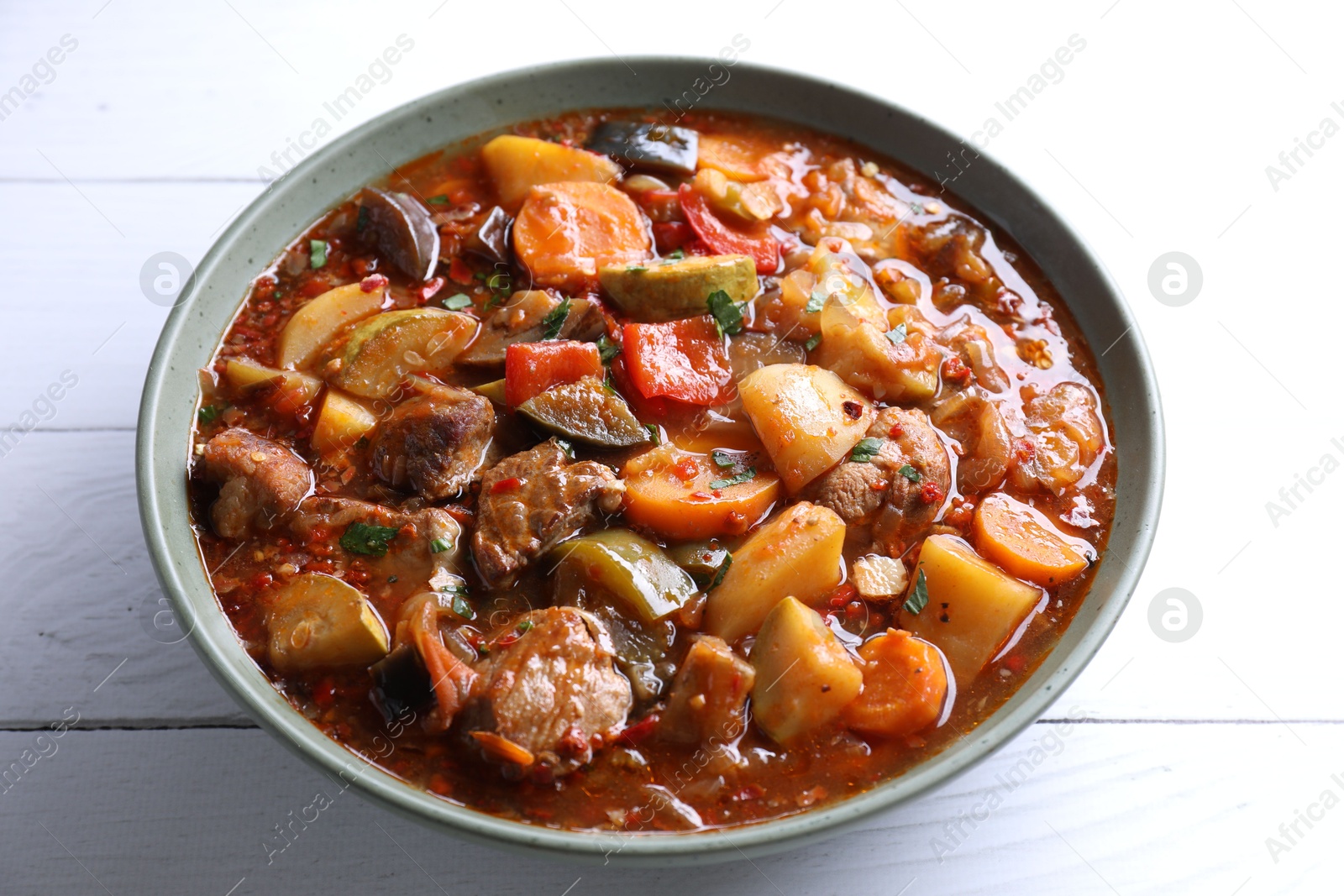 Photo of Delicious stew with vegetables in bowl on white wooden table, closeup