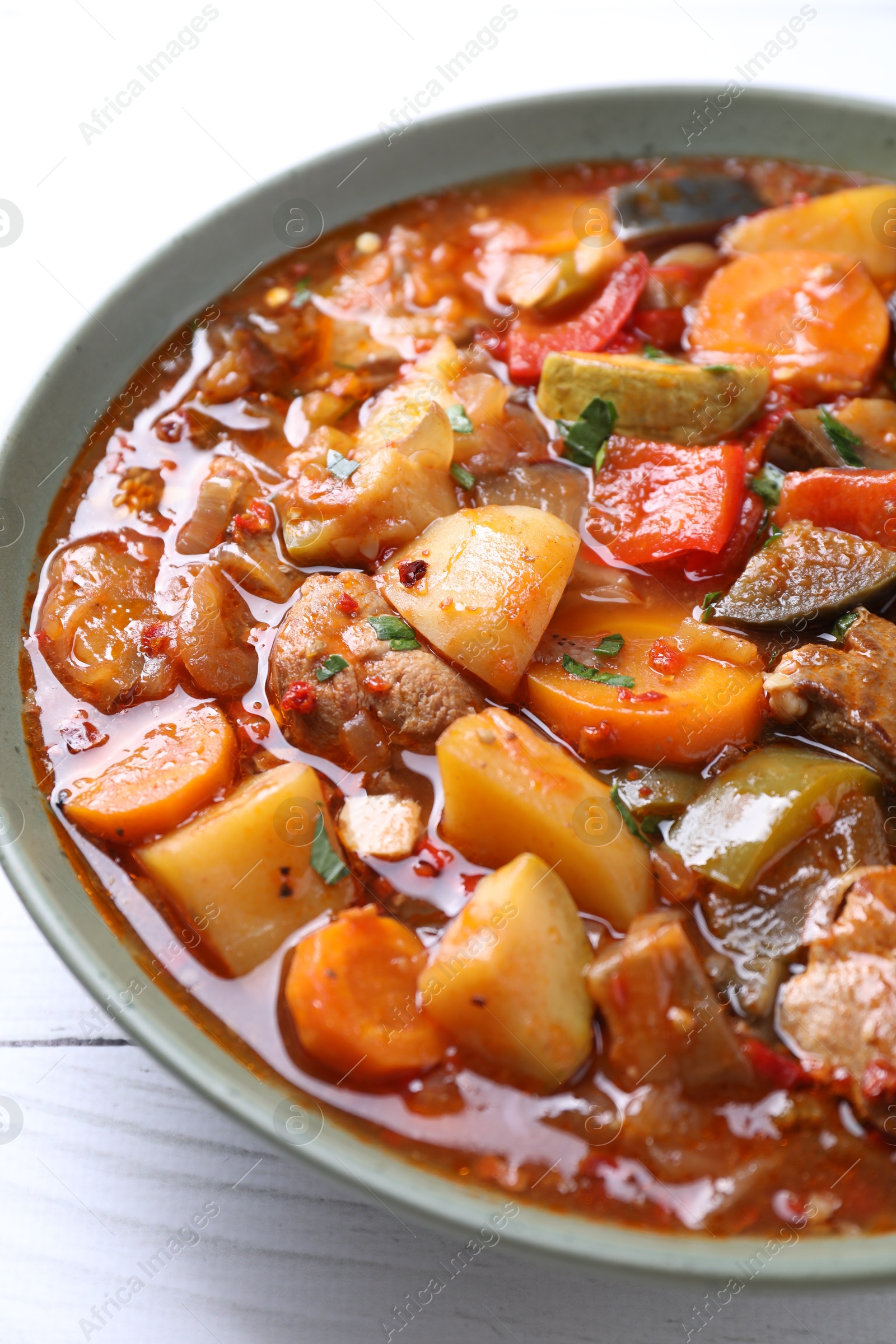 Photo of Delicious stew with vegetables in bowl on white wooden table, closeup