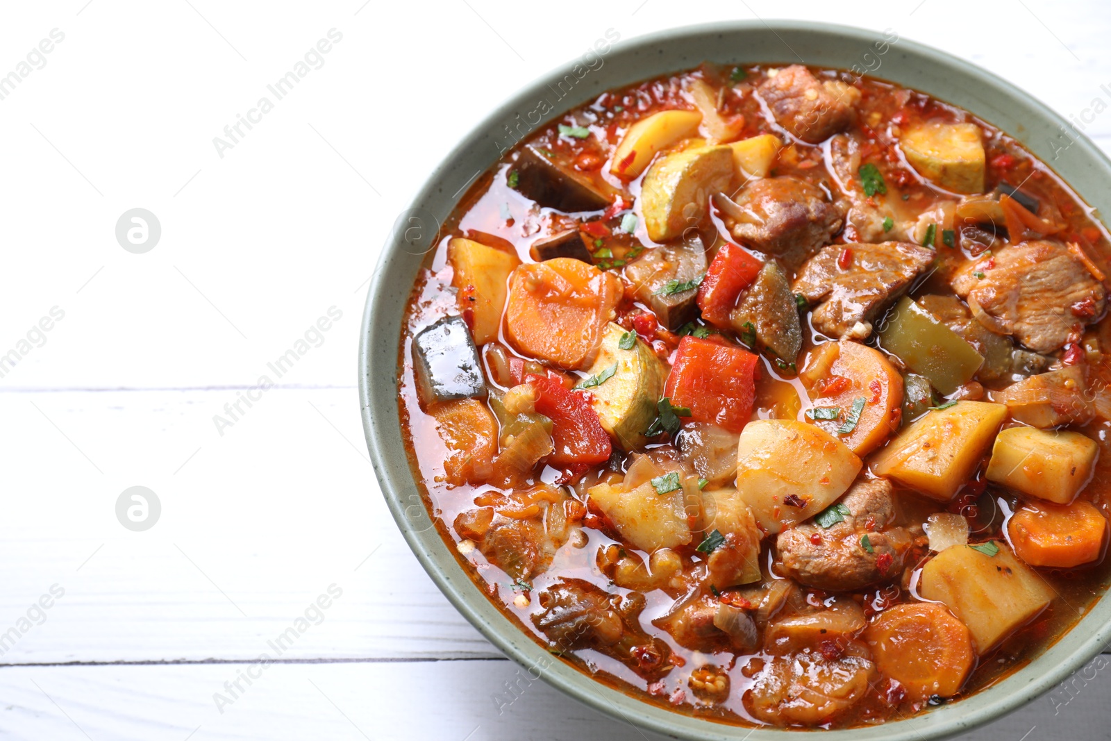 Photo of Delicious stew with vegetables in bowl on white wooden table, closeup