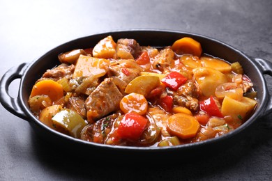 Photo of Delicious stew with vegetables in baking dish on grey table, closeup