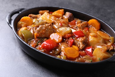 Photo of Delicious stew with vegetables in baking dish on grey table, closeup