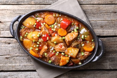 Photo of Delicious stew with vegetables in baking dish on wooden table, top view