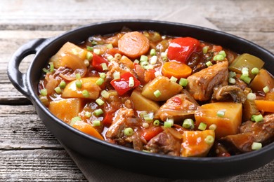 Delicious stew with vegetables in baking dish on wooden table, closeup