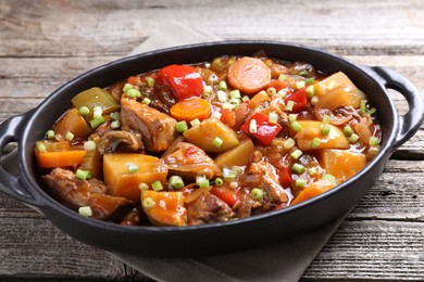 Delicious stew with vegetables in baking dish on wooden table, closeup